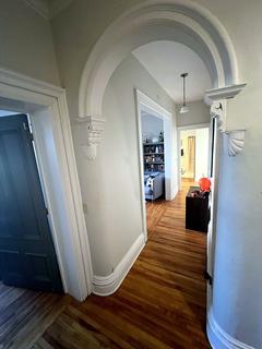 Hallway with arched doorway and hardwood floor