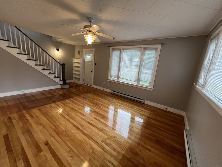 Living room with hardwood floor, staircase and front door